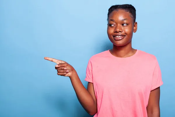 Портрет усміхненої афроамериканської молодої жінки, що вказує пальцем ліворуч — стокове фото