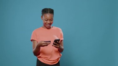 Genç yetişkin akıllı telefondan alışveriş yapmak için kredi kartı kullanıyor.