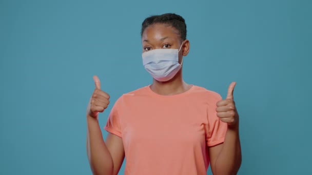 Portret van een casual persoon met gezichtsmasker met duimen omhoog teken — Stockvideo