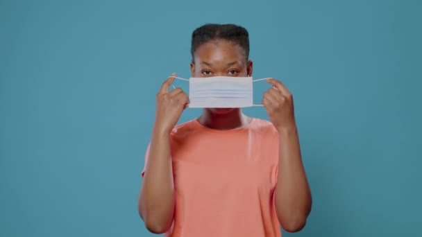 Portret van een jonge vrouw die een beschermend masker op haar gezicht zet — Stockvideo