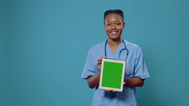 Pielęgniarka pionowo trzymająca tabletkę z zielonym ekranem — Wideo stockowe