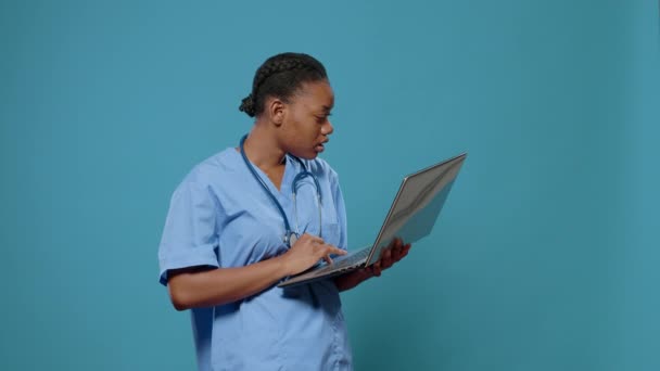 Retrato de enfermeira médica de uniforme olhando para a exibição do laptop — Vídeo de Stock