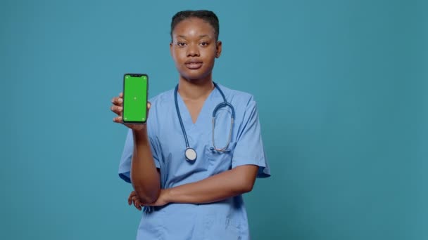 Portret asystenta medycznego trzymającego smartfona z zielonym ekranem — Wideo stockowe