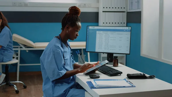 Infirmière afro-américaine utilisant une tablette numérique pour le traitement — Photo
