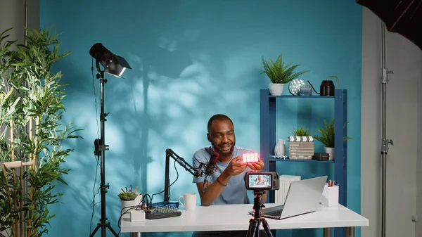 Hombre mostrando producto en cámara y filmando vlog — Foto de Stock
