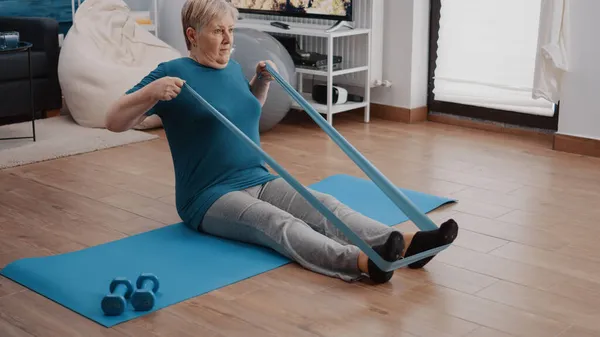 Aged person using elastic resistance band to exercise — Stock Photo, Image