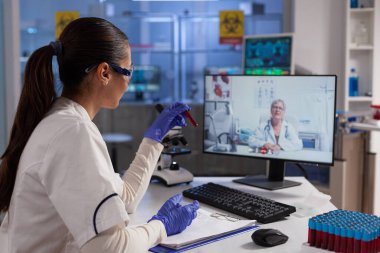 Uzaktan kumandalı doktorla konuşan, enfeksiyon kapmış kanla test tüpü tutan bir terapist.