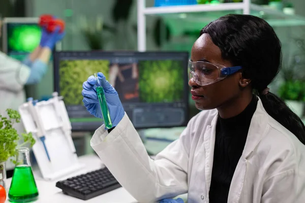 Investigador biólogo afroamericano sosteniendo tubo de ensayo médico con solución verde —  Fotos de Stock