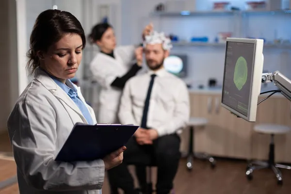 Medizinische Neurologin Frau Anpassung eeg Headset Überwachung der Gehirnaktivität des Mannes Patient — Stockfoto