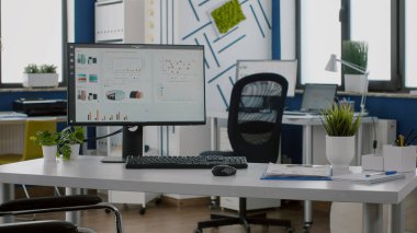 Bilgisayar boş iş yerinde, ekranda ve tekerlekli sandalyede grafikler var.