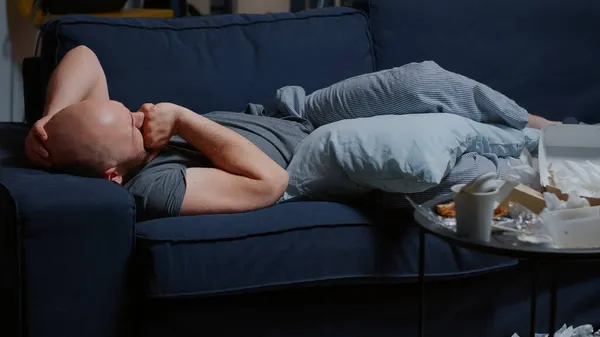 Depressed upset man caused by break up lying on sofa