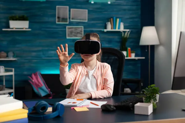 Schoolchild tentando fone de ouvido realidade virtual enquanto sentado na mesa de mesa — Fotografia de Stock