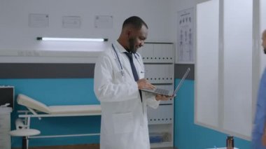 Afro-Amerikan terapist doktor elinde tablet bilgisayarla hastanede duruyor.