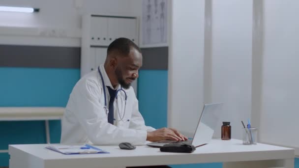Afrykański lekarz-terapeuta siedzi przy biurku w szpitalu analizując raport diagnostyczny choroby. — Wideo stockowe