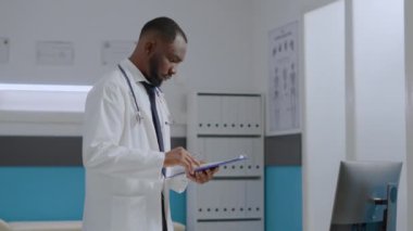 Afrika kökenli Amerikalı uzman doktor hastalık raporlarını inceliyor. Tıbbi uzmanlığı analiz ediyor.