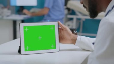Afrikalı Amerikalı uzman doktor yeşil ekran krom anahtar tabletinin modelini yapıyor.