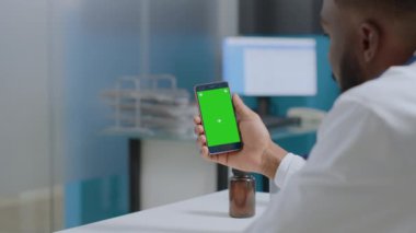 Afrikalı Amerikalı terapist elinde yeşil ekran krom anahtar akıllı telefon tutuyor.
