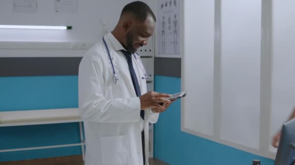 Médico terapeuta especialista afroamericano analizando informe de enfermedad usando tableta — Vídeos de Stock