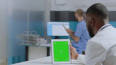 Afrikalı Amerikalı terapist yeşil ekran krom anahtar tabletini taklit etmeye çalışıyor.
