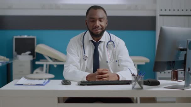 Retrato del médico afroamericano sentado en el escritorio analizando informe diagnóstico de enfermedad — Vídeos de Stock