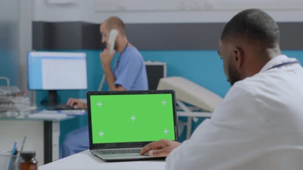 Αφροαμερικανός γιατρός που εξετάζει το πρότυπο μέχρι πράσινο chroma οθόνη κλειδί φορητό υπολογιστή — Αρχείο Βίντεο