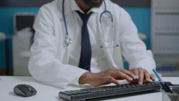 Retrato del médico especialista afroamericano sentado en el escritorio escribiendo tratamiento de medicamentos — Vídeos de Stock