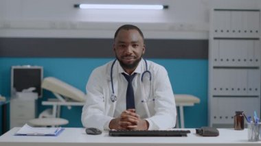 Bir sürü Afrikalı Amerikalı uzman doktor hastane ofisinde masasında oturuyor.