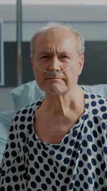 Burun tüpü ayakta duran yaşlı bir hastanın portresi.
