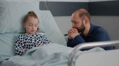 Burun tüpü takan hasta küçük kız ve parmak oksimetreleri oksijen doygunluğunu izliyor.