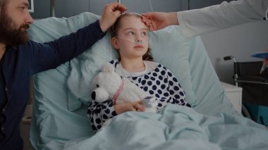 Endişeli baba, muayene sırasında hastaneye kaldırılan kızıyla oturuyor.