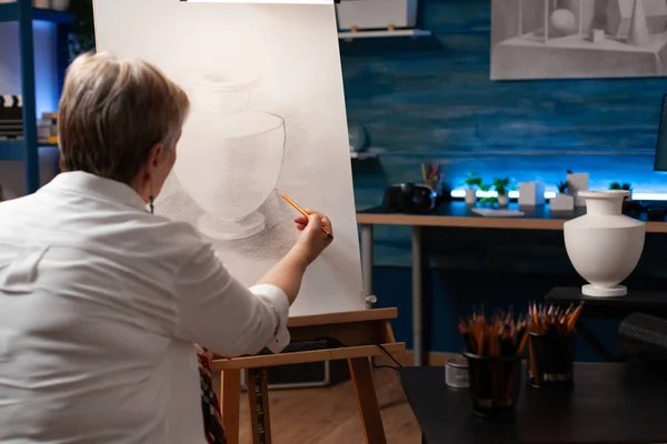 Artiste âgé caucasien travaillant avec vase et crayon sur toile — Photo