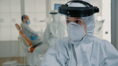 Ağız bakımı üzerinde çalışan tehlikeli madde giysisiyle dişçilik hemşiresini kapatın.