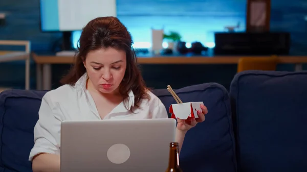 Жінка використовує ноутбук для бізнесу та їсть азіатську їжу — стокове фото