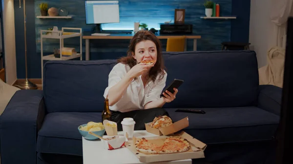 Empresaria usando smartphone mientras come rebanada de pizza — Foto de Stock