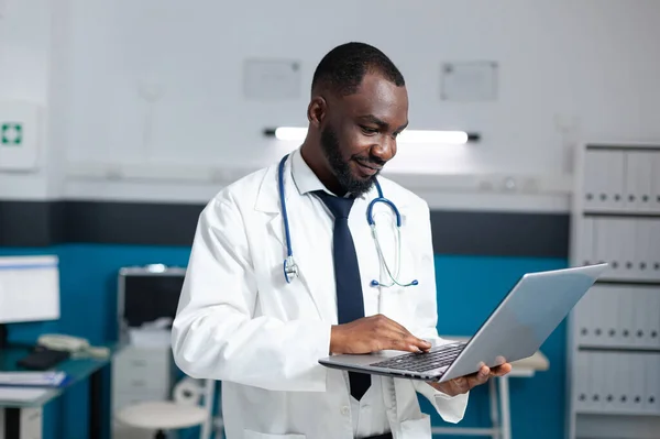 Afroamericano terapeuta medico in possesso di computer portatile guardando prescrizione medica online — Foto Stock