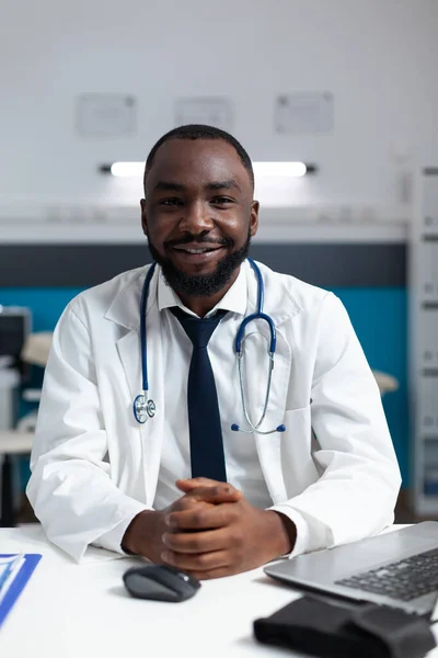 Retrato de terapeuta afro-americano médico sentado à mesa no escritório do hospital — Fotografia de Stock