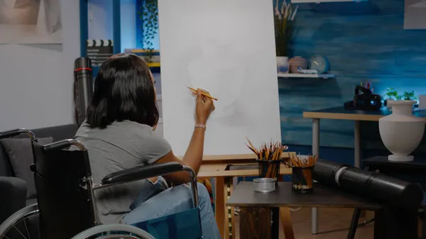 Svart konstnär med handikapp med penna på duk — Stockfoto
