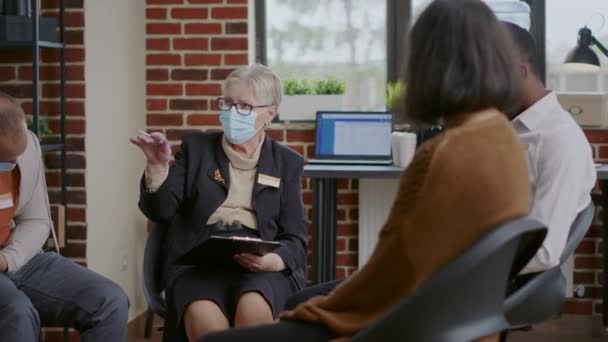 Κοντινό πλάνο της ψυχιάτρου γυναίκα μιλάει με τους ανθρώπους σε μια ομαδική θεραπεία, φορώντας μάσκα προσώπου — Αρχείο Βίντεο