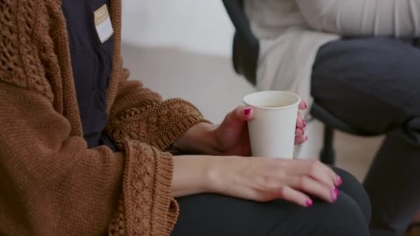 Primer plano de la mujer nerviosa sosteniendo una taza de café y temblando en la reunión de terapia aa — Vídeo de stock