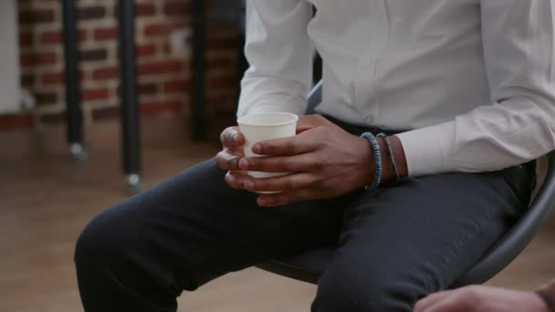 Közelkép afro-amerikai férfi, aki ideges, miközben egy csésze kávét tart egy találkozón. — Stock videók