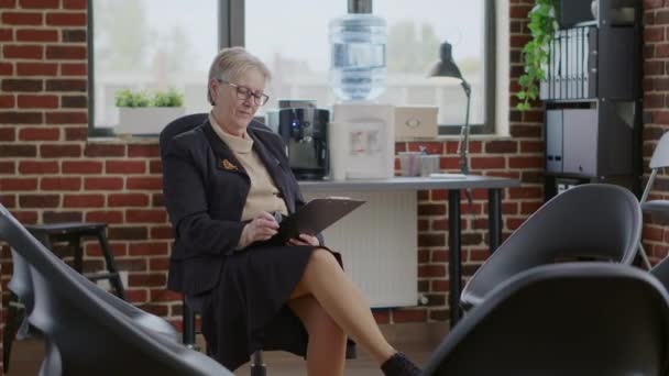 Portrait of woman psychologist holding clipboard in circle with chairs for aa group meeting — Stok Video