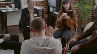 Öfke kontrolü sorunu olan bir adam AA grup toplantısında insanlarla konuşuyor ve danışmanlık yapıyor.