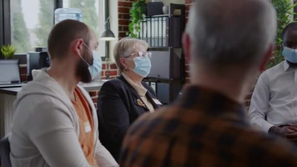 Psychiatra rozmawiający z ludźmi na spotkaniu grupy AA na sesję terapeutyczną, noszący maskę na twarzy — Wideo stockowe