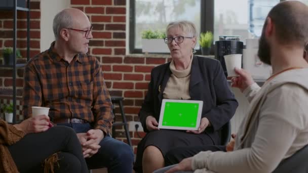 Терапевт держит планшет с горизонтальным зеленым экраном на встрече с людьми — стоковое видео
