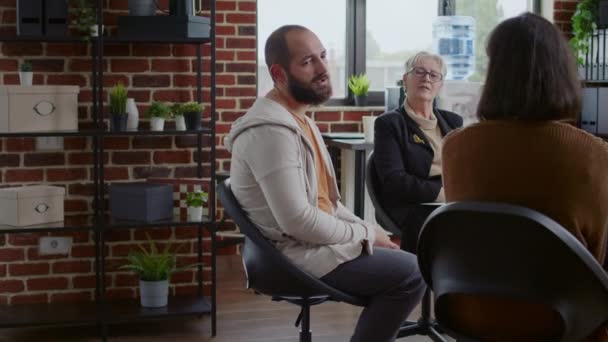 Frustrado homem compartilhando história com grupo de pessoas e terapeuta na reunião de terapia aa — Vídeo de Stock