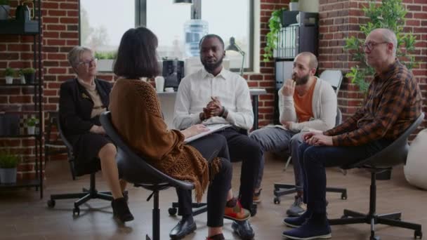 Africano americano homem compartilhando história de vício com grupo de pessoas em aa reunião de terapia — Vídeo de Stock