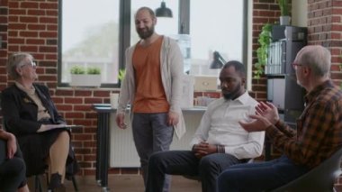 Bağımlılığın ilerlemesini kutlayan neşeli bir adam. A.A. grup toplantısında insanlar alkışlıyor.