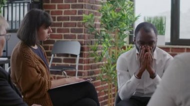 Adsız Alkolikler 'deki insanlar akıl sağlığı sorunları ve bağımlılığı olan bir adamı rahatlatıyorlar.