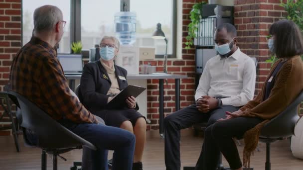 Терапевт дает советы мультиэтнической группе людей в маске на встрече в Аа — стоковое видео