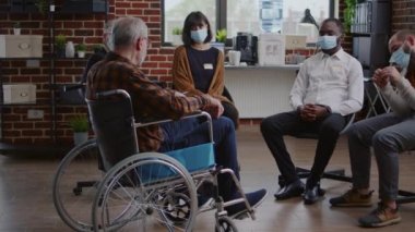 Engelli kıdemli bir adam salgın sırasında insanlarla grup terapisine katılıyor.